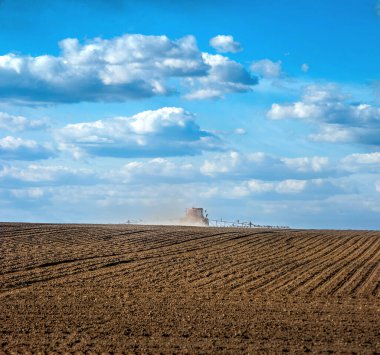 İlkbaharda ekilebilir tarlalar ve kendi kendine çalışan bir püskürtücü tarım alanlarına ve dikiz manzarasına gübre saçıyor.