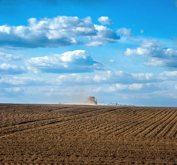 İlkbaharda ekilebilir tarlalar ve kendi kendine çalışan bir püskürtücü tarım alanlarına ve dikiz manzarasına gübre saçıyor.