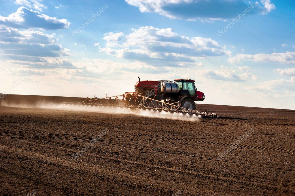 self-propelled sprayer in the field makes fertilizers in early spring, backlit jet
