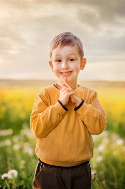 Baharda karahindiba ve ırz tohumlarının yanında gülümseyen mutlu çocuk.
