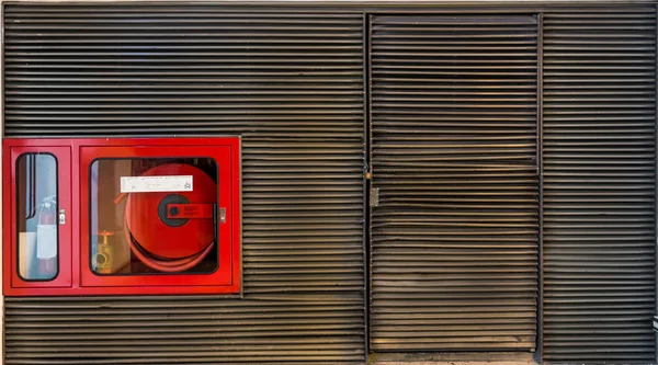 Tűzoltó készülék szekrényben a grunge fém léc fal zsaru — Stock Fotó