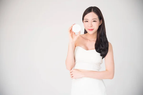 Asiatisk kvinna håller kosmetika makeup produkt isolerad på vita b Stockbild