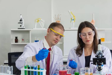 Kadın ve erkek bilim adamı güvenlik gözlükleri laboratuarda kimyasalla deney yapıyorlar.