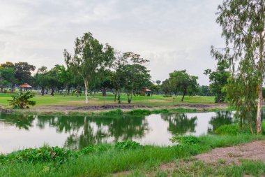 Çimenli golf sahası ve havuzdaki ağaçların yansıması spor yapmak için güzel bir manzara yaratıyor.