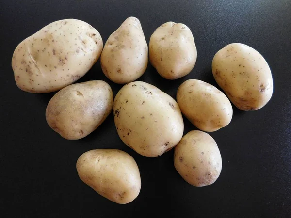 Batatas em um fundo preto — Fotografia de Stock