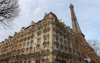 Tipik balkonları, pencereleri ve arka planında Eyfel kulesi olan geleneksel Fransız evi. Paris.