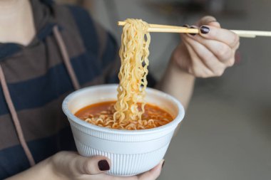 Bir kase hazır erişte ellerinde çubuklarla ramen, yakın çekim.