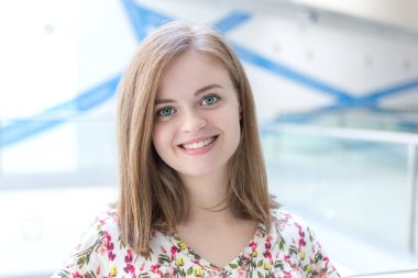 Gülümseyen, güzel, beyaz, çiçekli tişörtlü bir kızın portresi.