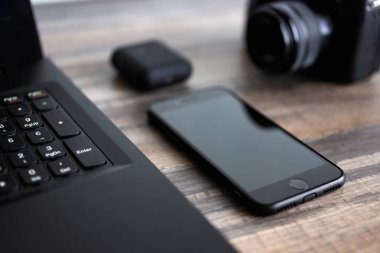 Fotoğrafçı ya da stok fotoğrafçılığı konsepti, bilgisayarın yanında dijital siyah kamera ve çalışma masasında telefon.