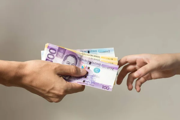Hand holding giving cash banknotes Philippines peso paying bills, payment procedure or bribe, salary