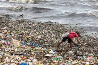 Manila, Filipinler - 23 Ağustos 2017: Denizdeki bir çöp yığını içinde plastik atık toplayan bir adam
