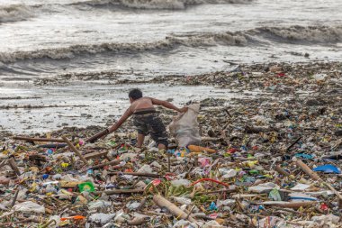 Manila, Filipinler - 23 Ağustos 2017: Denizdeki bir çöp yığını içinde plastik atık toplayan bir adam