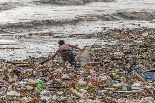 Manila, Filipinler - 23 Ağustos 2017: Denizdeki bir çöp yığını içinde plastik atık toplayan bir adam