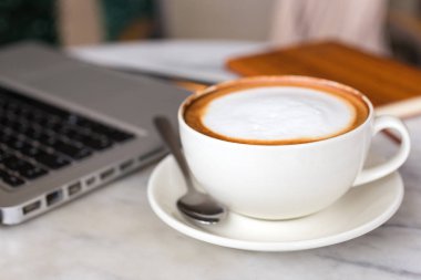 Masada iş için kahve fincanı ve laptop, makroyu kapatın.