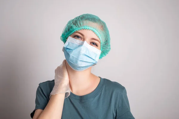 Cerrahi maske takan beyaz kadın doktor yorgun görünüyor.
