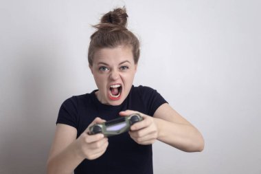 Kızgın genç beyaz kadın elinde joystick oyun konsolu ile bilgisayar oyunu oynuyor..