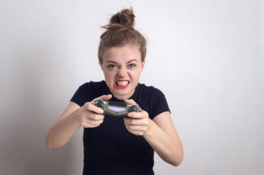 Kızgın genç beyaz kadın elinde joystick oyun konsolu ile bilgisayar oyunu oynuyor..