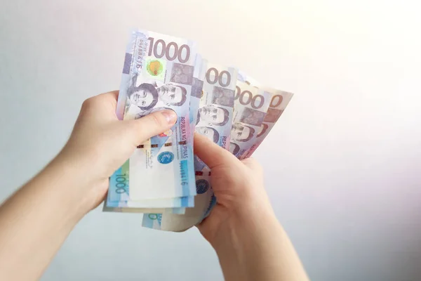 Bin Filipinli pezonun nakit banknotunu tutan eller. Faturalar, ödeme ya da maaş. Beyaz arkaplan, kapat