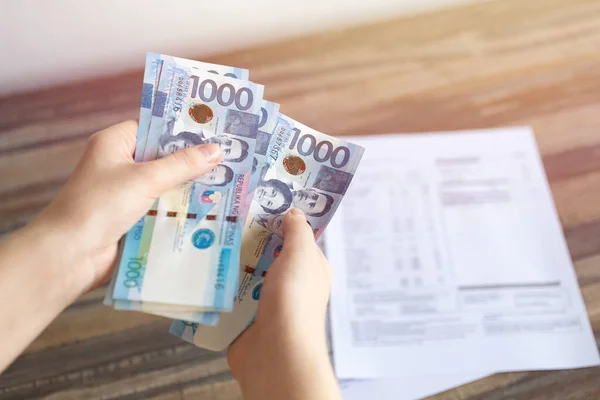 000フィリピンペソの現金銀行券を持っている手は 請求書 支払いまたは給与を支払う 白地を閉じて ストックフォト