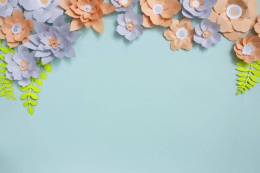 Renkli kağıt çiçeklerin düz çerçevesi mavi arkaplanda sol köşede. Üst görünüm, kopyalama alanı, çiçek sanatı