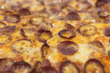 Büyük peynirli pepperonili pizza ve arka plan makrosu.