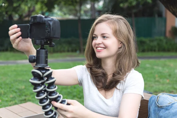 若いですCaucasian女の子作るビデオブログ Vlog とともにカメラの外で緑の公園 — ストック写真