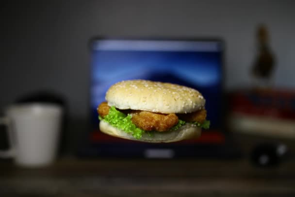 一个汉堡在笔记本电脑前旋转的无缝镜头 网上或逾期订餐概念 — 图库视频影像