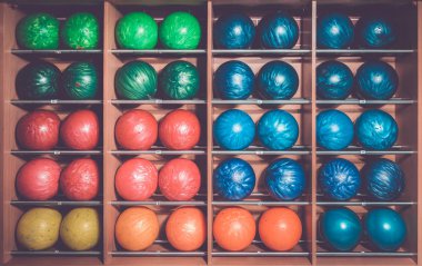 Bowling topları rafta, boyut ve renge göre sıralanmış.