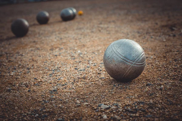 Petanque balls on a sandy pitch with other metal ball in the bac — Stock Photo, Image