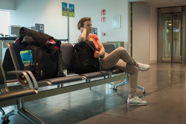Молодая женщина с багажом ждет в зале аэропорта свой самолет — стоковое фото