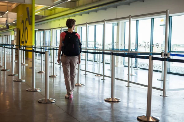 Ung kvinna med bagage som väntar i flygplats hallen hennes plan — Stockfoto