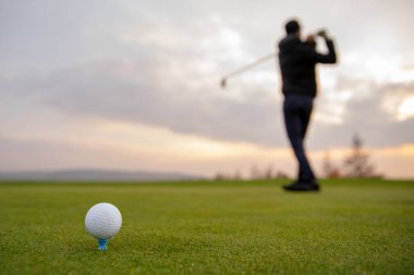 Bir golfçü topu golf sahasında ateşlenmeye hazırlar.