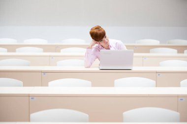 Üniversite konferansında dizüstü bilgisayarla çalışan genç ve güzel bir kadın.