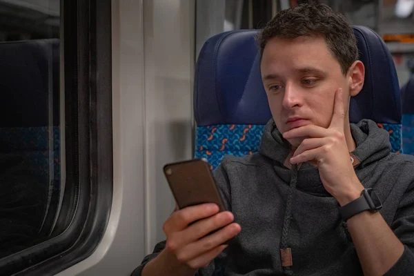 Joven en el tren lee noticias en su smartphone — Foto de Stock