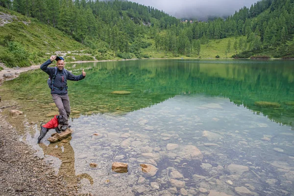 Excursionistas en los alpes austriacos caminan por senderos de montaña en los bosques alrededor de los lagos con perro negro —  Fotos de Stock