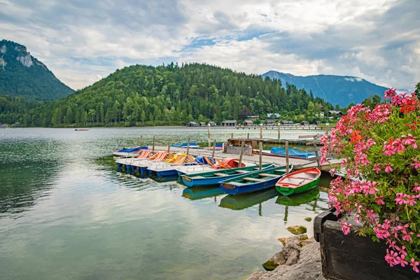Βάρκες σε μια βουνίσια λίμνη έτοιμες να δανείσουν τουρίστες για κολύμπι στη γαλάζια επιφάνεια του νερού — Φωτογραφία Αρχείου