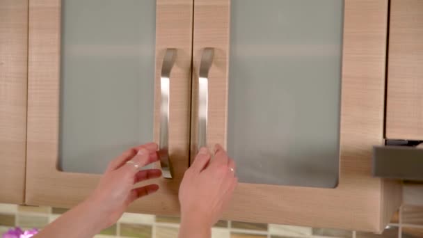 Kvinna drar mugg ur köksskåpet och stänger skåpsdörren — Stockvideo