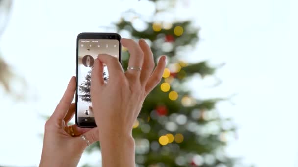 Farklı renklerde süslenmiş ve parlayan akıllı telefon yılbaşı ağacıyla fotoğraf çekimi. — Stok video