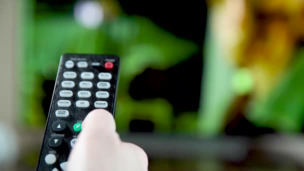 The remote control switches the TV channels and controls the volume — Stock Video