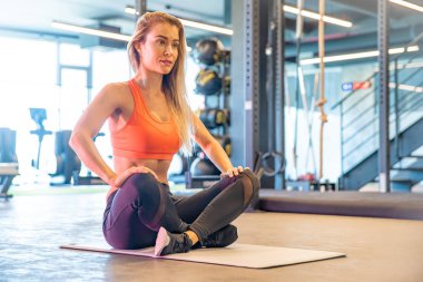 Genç ve güzel bayan egzersizden önce spor salonunda geriniyor.