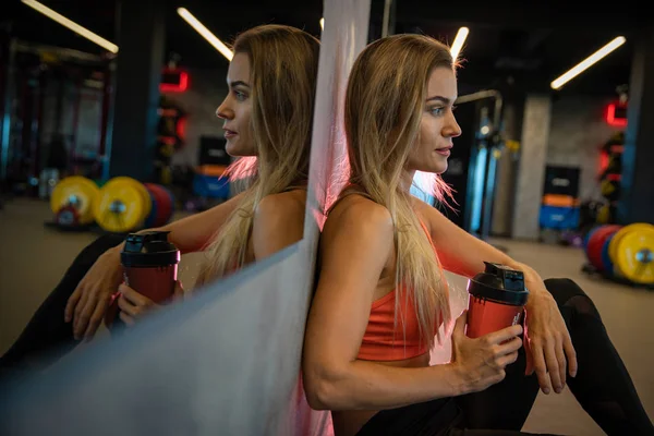 Joven bonita mujer descansando en el gimnasio después del ejercicio — Foto de Stock