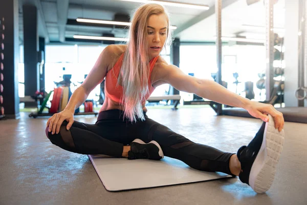 Young pretty woman is stretching in the gym before exercise — 스톡 사진