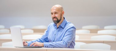 Lisedeki konferans salonunda beyaz dizüstü bilgisayarlı bir öğrenci.