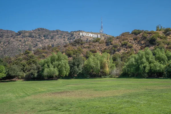 Зеленый луг перед холмом с голливудскими письмами, сделанными для туристов, фотографирующих символ Америки — стоковое фото