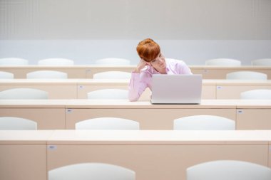 Öğrenci dersten sonra sınıfta zor bir görev üzerinde düşünür.