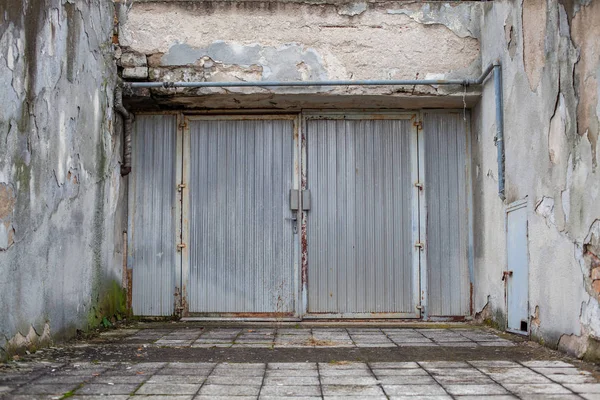 Una vieja puerta de metal en un edificio medio arruinado de una ciudad abandonada —  Fotos de Stock