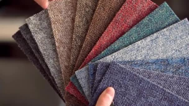 Mężczyzna wybiera kolor nowego dywanu zgodnie z wzorem książki w sklepie z podłogami — Wideo stockowe