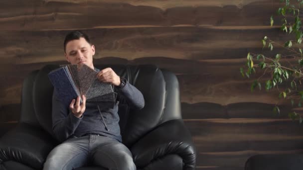 Muž si vybere barvu nového koberce podle vzoru knihy v dílně — Stock video