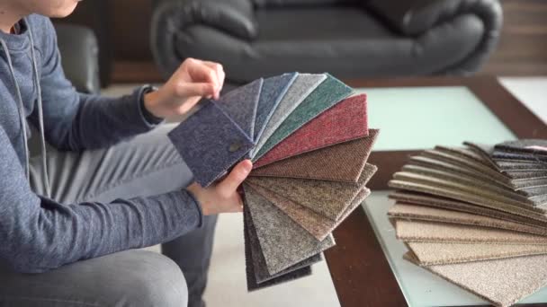 O homem escolhe a cor do novo tapete de acordo com o livro padrão na loja de pisos — Vídeo de Stock