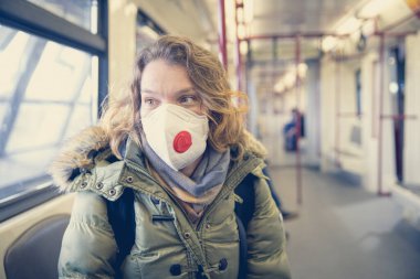 Metroda kafasında solunum cihazıyla bir yolcu gibi duran bir kadın. Koronavirüs salgınına karşı koruma